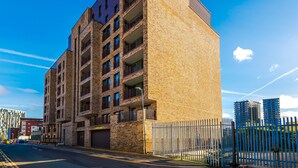 A multi-story building with a brick facade, multiple balconies, and a gated entrance.