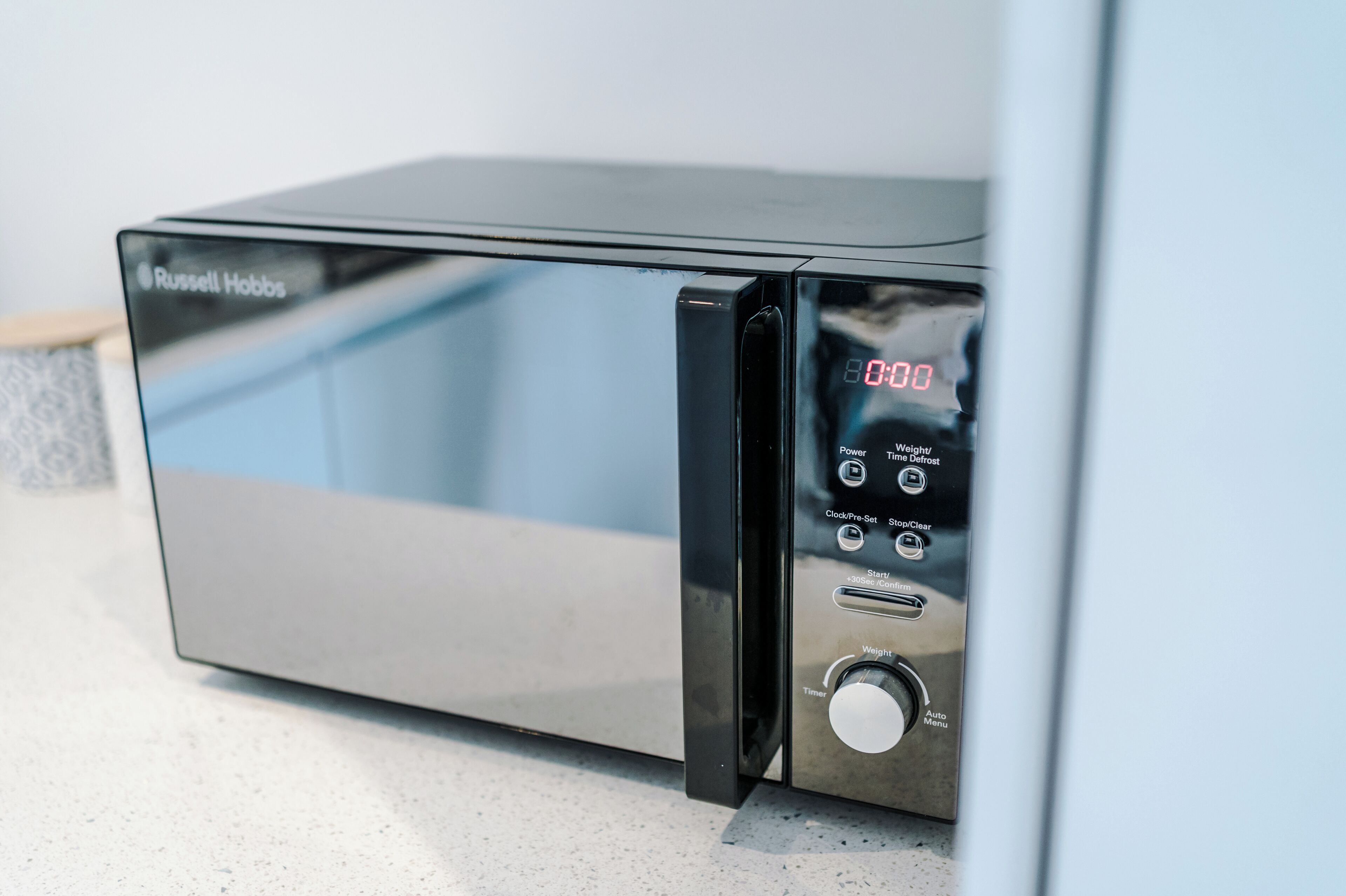 Eine moderne Mikrowelle mit digitaler Anzeige, Power-Taste, Timer und Start-/Stopp-Knöpfen.