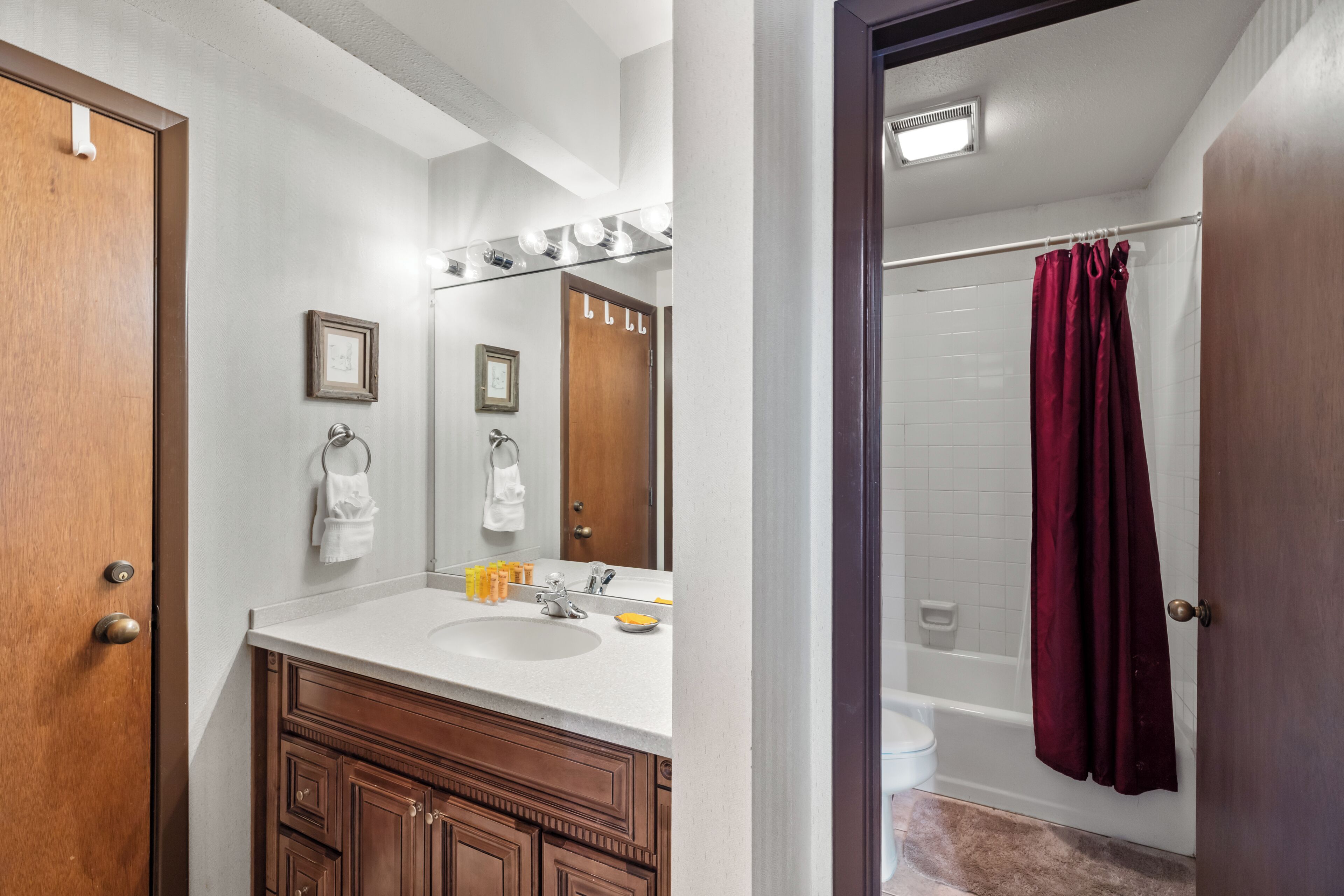 A bathroom with a wooden door, a white sink, a mirror, and a shower curtain.