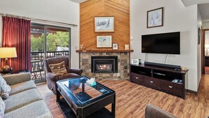 A living room with a fireplace, a flat-screen TV, and a comfortable seating area with a sofa and armchairs. - Cozy Mountain Retreat at Timber Run 101! (Steamboat Springs)