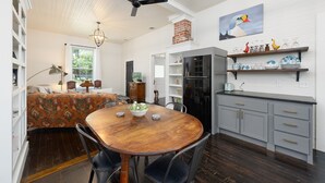 Une cuisine moderne avec une table à manger en bois, des meubles de couleur grise et une cheminée en briques.