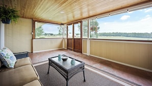 A room with a wooden ceiling, a cushioned bench, a wicker table, and a view of the outdoors. - 5BR Retreat On Acreage Near KC (Liberty)