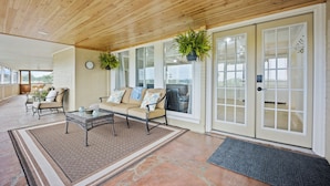 A spacious living area with a wooden ceiling, a beige sofa, a coffee table, and a large window with a view. - 5BR Retreat On Acreage Near KC (Liberty)
