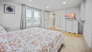 A bedroom with a bed, a dresser, a television, and a window with curtains. - 5BR Retreat On Acreage Near KC (Liberty)