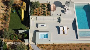 Vista a érea de un moderno complejo turístico con piscina, mobiliario exterior y bañera de hidromasaje.
