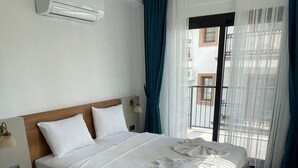 Une chambre d’hôtel moderne dotée d’un grand lit, d’une table de chevet, d’un appareil de climatisation et offrant une vue sur le balcon extérieur.