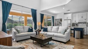Una sala de estar moderna con un conjunto de sofás, una mesa de centro y vistas al exterior a través de grandes ventanales.