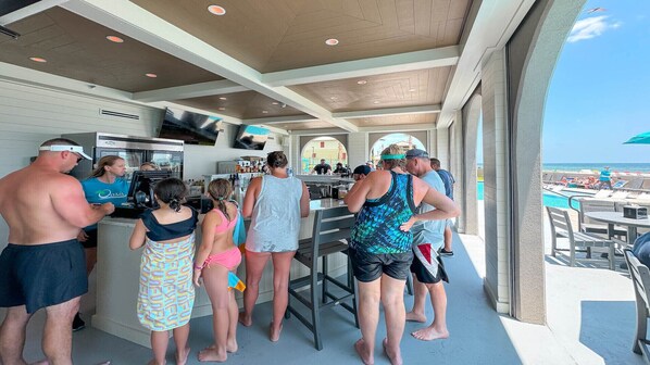 A poolside bar area with people standing and conversing. - New Rental! Lazy River/Slide! Restaurant/Bar Onsite!!! (Orange Beach)