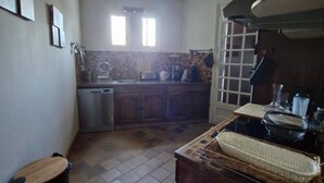 A kitchen with a stove, sink, and a window. There are hanging lights and a trash bin. - Villa en plein coeur d'Uzès (Uzès)