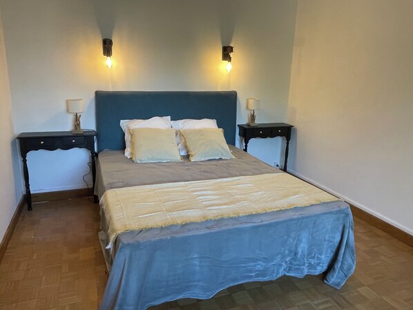 Une chambre à coucher avec un lit, deux tables de chevet et des lampes fixées au mur.