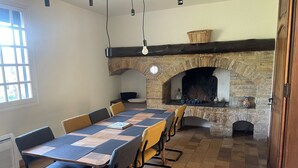 A dining area with a long table, chairs, and a stone fireplace. - Villa en plein coeur d'Uzès (Uzès)
