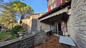A stone building with a tiled patio, a table, and chairs. - Villa en plein coeur d'Uzès (Uzès)