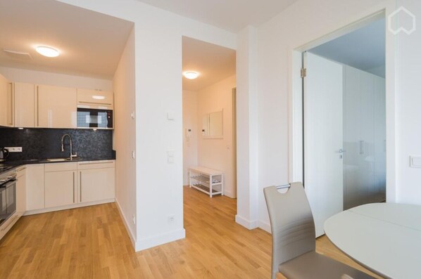 A modern apartment with a kitchen, dining area, and a small seating space.