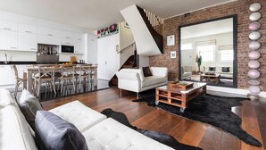A modern living space with a kitchen, dining area, and a staircase leading to an upper level. - Codrington Mews III by Onefinestay (London)