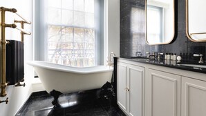 Un bagno con una vasca freestanding, uno specchio grande e una finestra con vista su una recinzione.