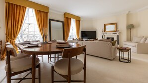 Una sala de estar con un sofá, una mesa de comedor con sillas, un televisor y una chimenea.