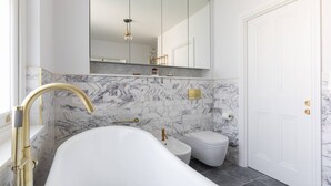 Een moderne badkamer met een vrijstaand bad, toilet en wastafel.