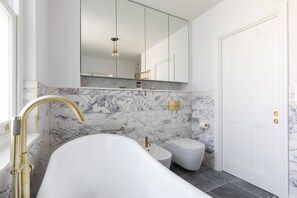 Een moderne badkamer met een vrijstaand bad, toilet en wastafel.