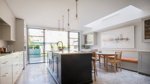 Een moderne keuken met een centraal eiland, grote ramen en hanglampen.