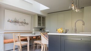 Een moderne keuken met een eetgedeelte, met een groot raam, een stadsgezicht schilderij en een bijzondere lamp.