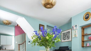 A dining room with a wooden table, two chairs, a vase with flowers, a piano, and a patterned rug. - Keystone Crescent by Onefinestay (London)