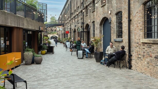 An outdoor café area with brick buildings, outdoor seating, and string lights. - Keystone Crescent by Onefinestay (London)