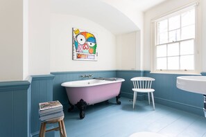 A bathroom with a clawfoot tub, a white sink, and a chair. - Keystone Crescent by Onefinestay (London)