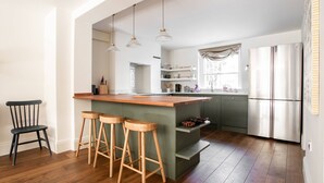 Een moderne keuken met een houten kookeiland, barstoelen en een roestvrijstalen koelkast.