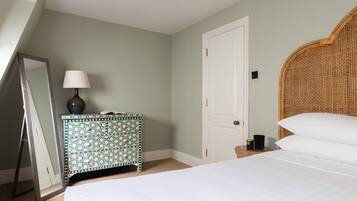 A bedroom with a bed, a dresser, a mirror, a lamp, and a door.