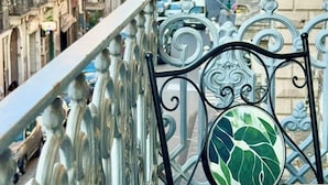 A balcony with ornate metal railings overlooking a street with historic buildings and a large dome structure in the distance. - Trewhella Home, centro storico, Duomo (Catania)