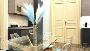 A modern kitchen with a glass dining table, clear chairs, and a decorative vase with feathers. - Trewhella Home, centro storico, Duomo (Catania)