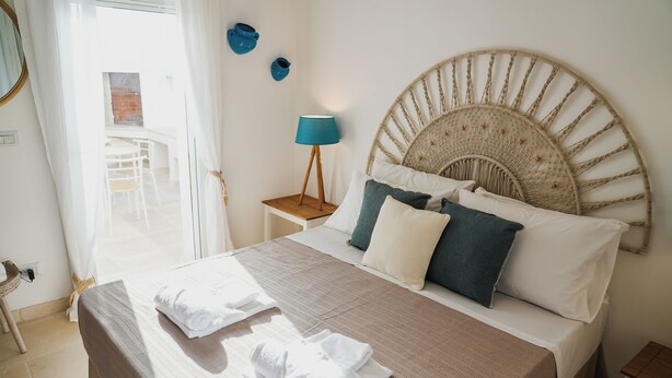 A neatly made bed with white and blue pillows, a wooden headboard, and a bedside lamp. - fraledune (Maruggio)