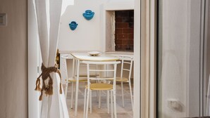 A narrow corridor with a white door, a small table with chairs, and a blue wall decoration. - fraledune (Maruggio)