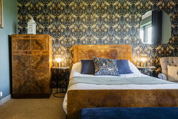 Une chambre à coucher avec un grand lit, une armoire, deux tables de chevet avec des lampes et un miroir au mur.