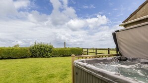 A hot tub in a backyard with a wooden fence and a hedge. - Gorgeous Rural 4 Bed Farm Cottage - With Hot Tub (Norton Saint Philip)