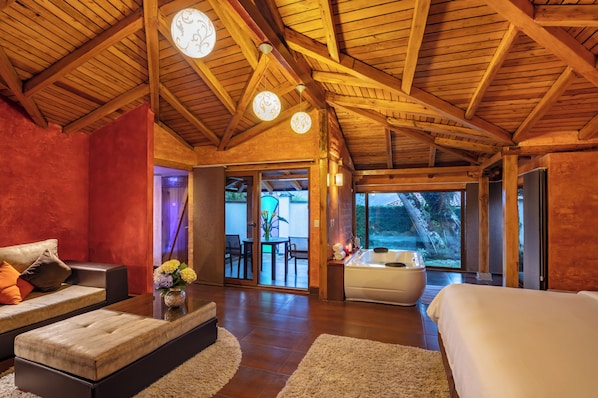 A spacious room with a wooden ceiling, a large bed, a sofa, and a view of the outdoors. - Luna Volcán, Adventure SPA - formerly Luna Runtún (Baños de Agua Santa)