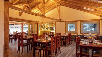 A restaurant with wooden beams, multiple dining tables, and chairs.