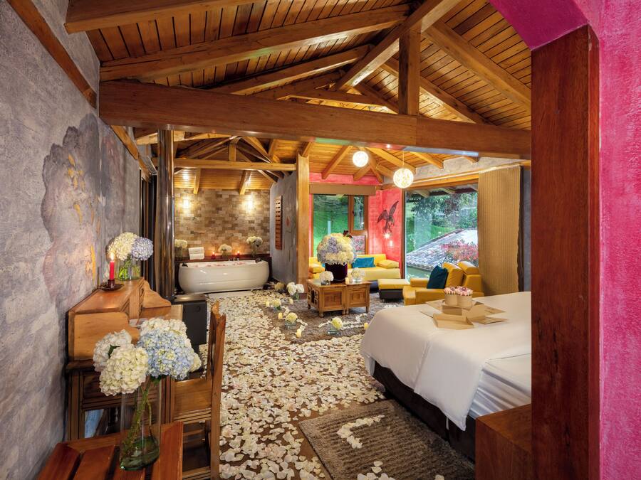 Een kamer met een houten plafond, een groot bed, een badkuip en een bank.