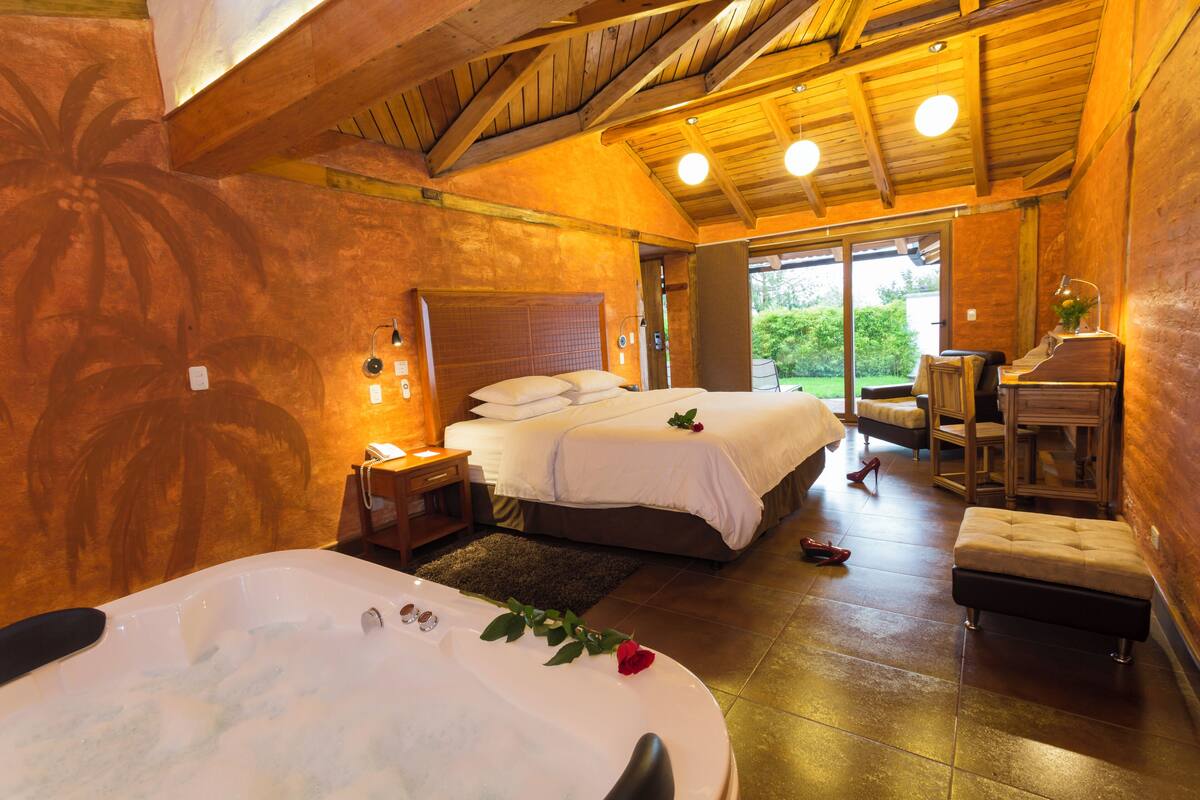 A room with two beds, a bathtub, and a wooden ceiling.