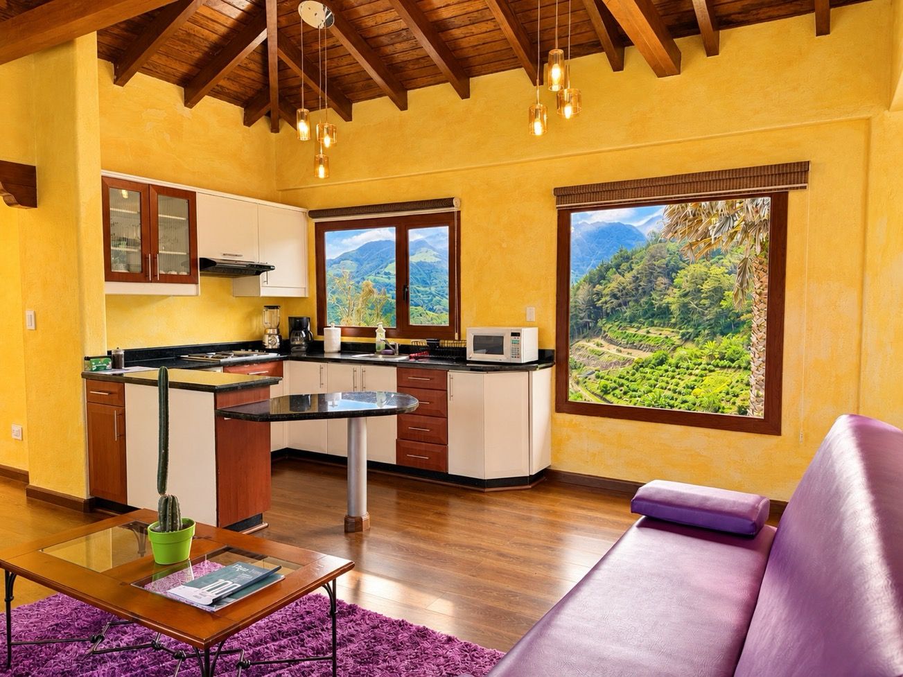 A kitchen with a view of a mountainous landscape, a dining table with a cactus, and a purple sofa.