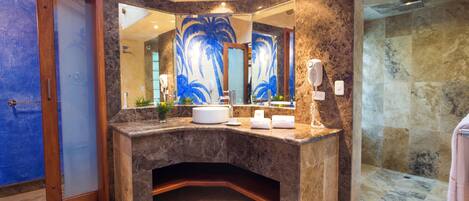 A bathroom with a marble vanity, a large mirror with a palm tree design, a shower area, and a blue door.