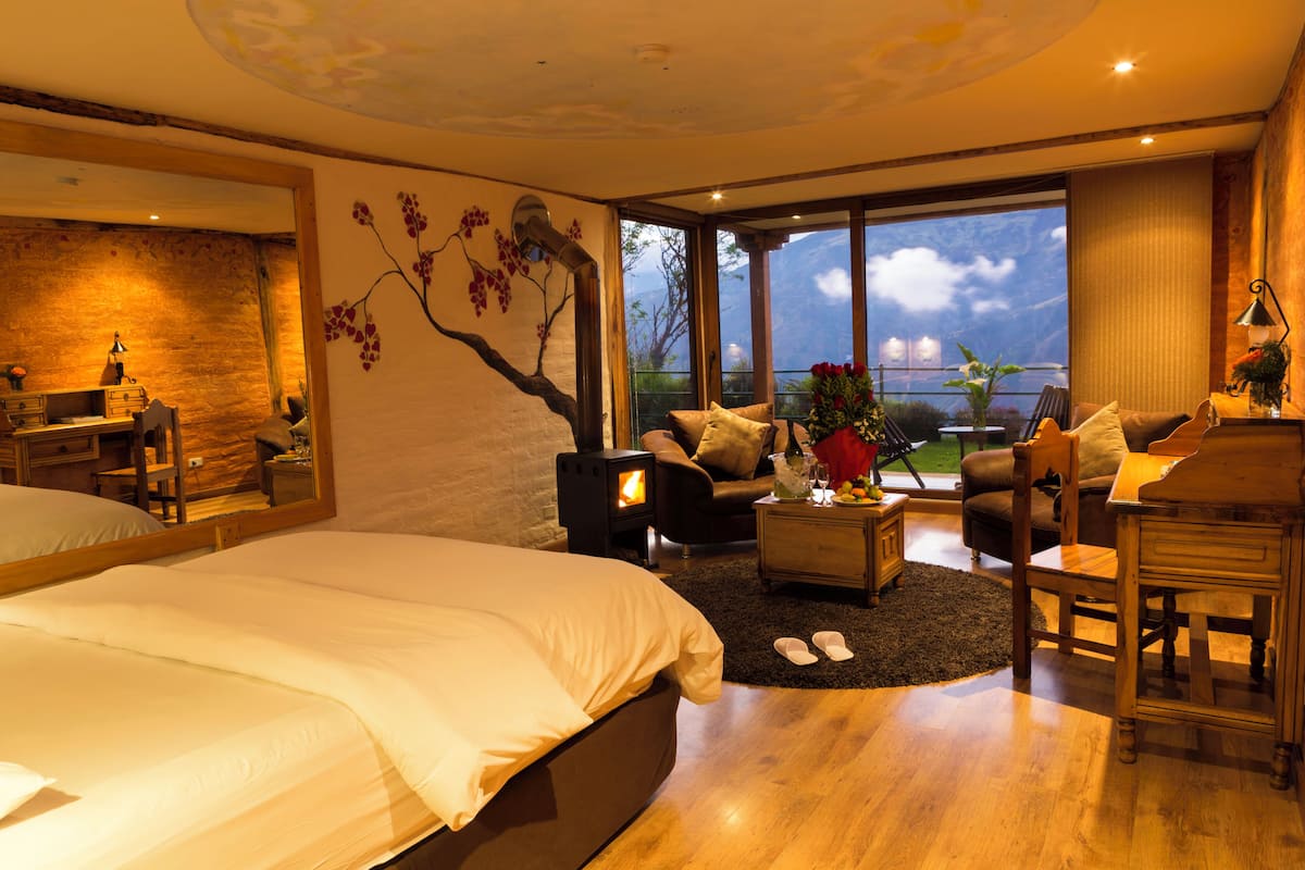 A modern bedroom with a large bed, a wooden coffee table, and a view of the outdoors.