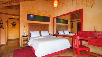 A bedroom with a large bed, a red desk, and a mirror.