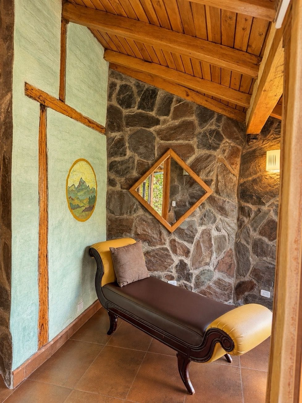 A stone wall with a wooden bench and a framed mirror.