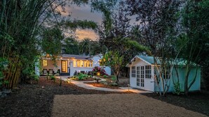 A house with a well-maintained garden, a small shed, and a pathway leading to the entrance.