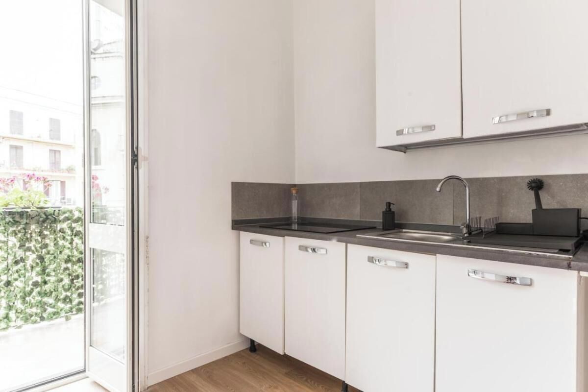 A modern kitchen with white cabinets, a black countertop, and a stainless steel sink.
