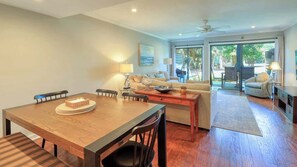 A spacious living area with a dining table, sofas, and a large sliding glass door leading to an outdoor area. - Villa w/ Golf Views! Pool, Near Beach Hilton Head (Hilton Head Island)