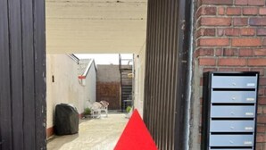 A red arrow pointing upwards, a metal mailbox, and a brick wall. - Apartments & Zimmer (Vettweiß)