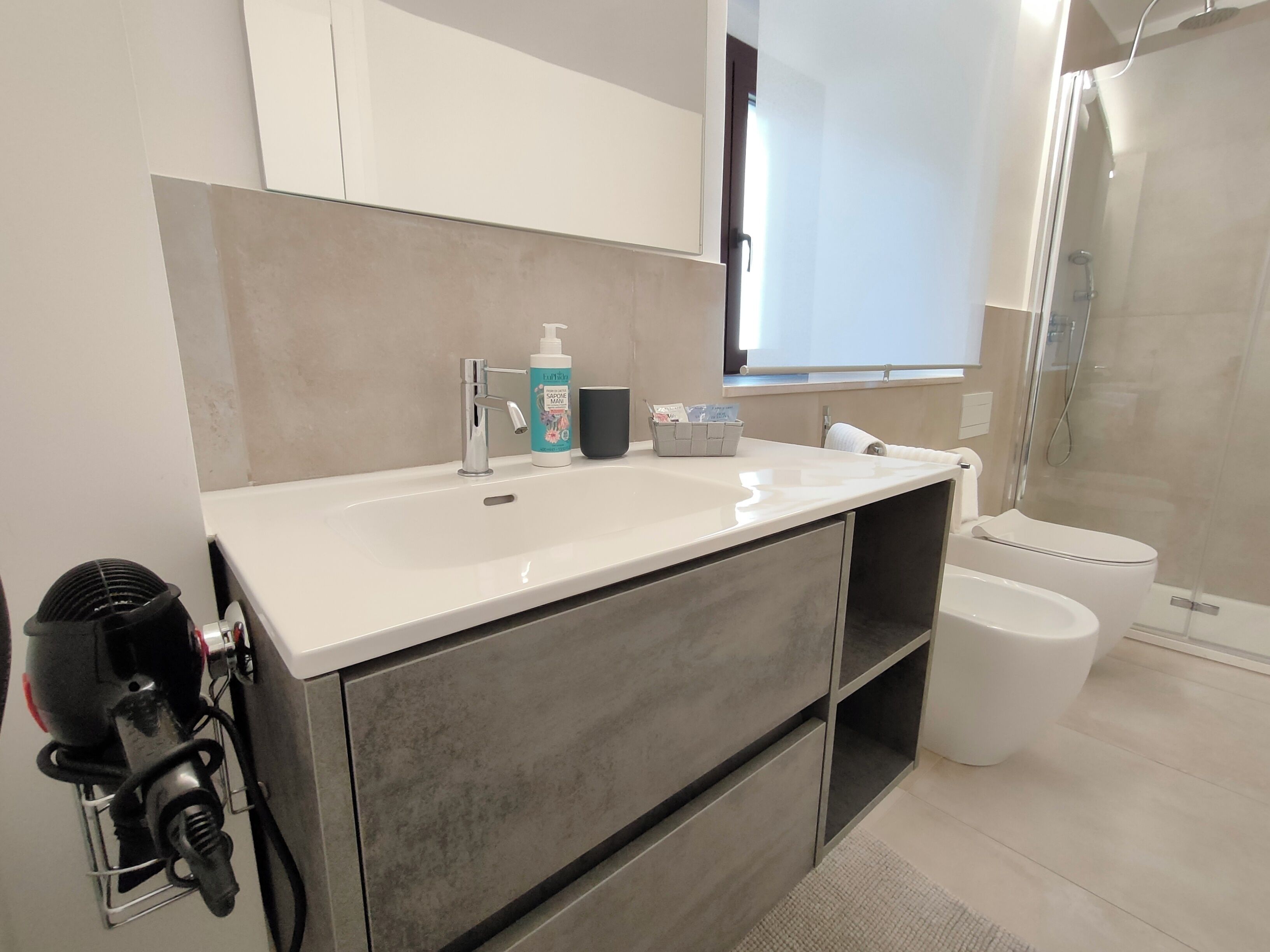 Une salle de bain moderne avec un lavabo blanc, une douchette à main et des toilettes.