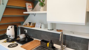 A modern kitchen with a coffee machine, a cutting board, a sink, and a potted plant.